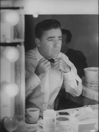 Actor Peter Lawford Using Dressing Room Mirror to Tie His Tie